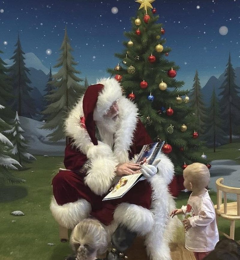 Santa reading a storybook to a toddler in front of a winter scene