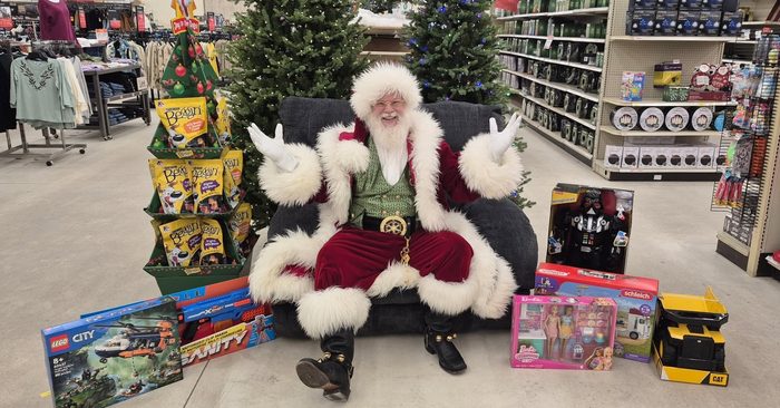 Santa seated among toys and Christmas trees at a local store