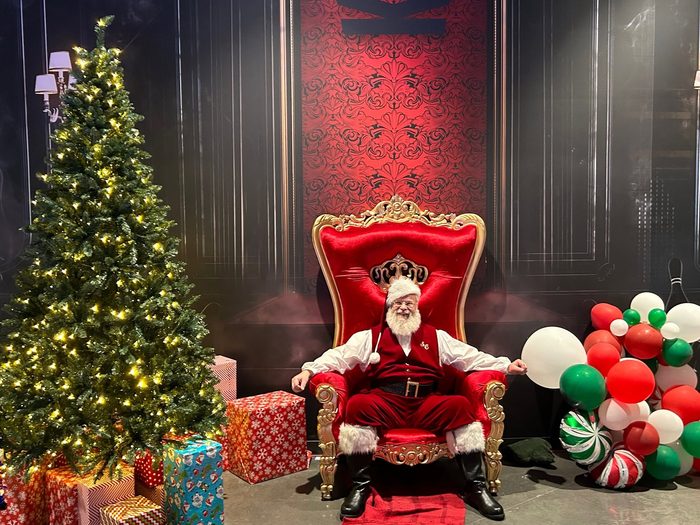 Santa on a red and gold throne beside the Christmas tree